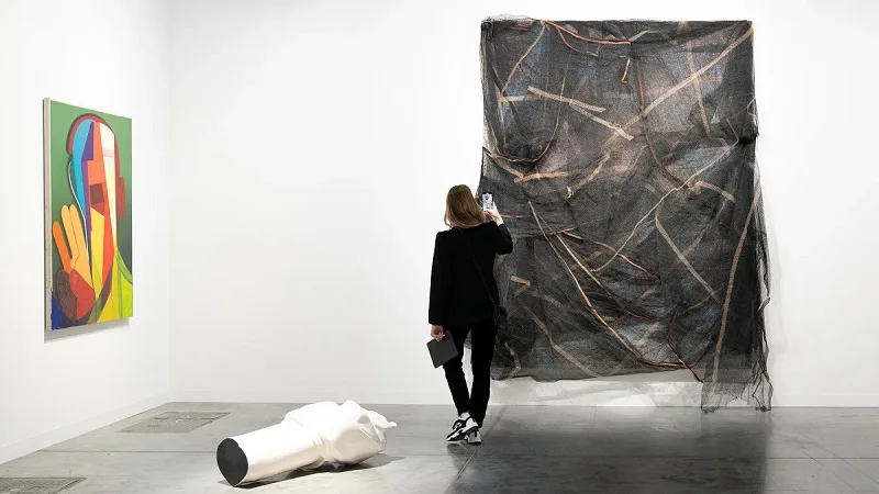 Una visitatrice dell'Art Basel Miami Beach fotografa Untitled del 2014 di David Hammons