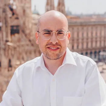 Un'immagine di Ivan Pivirotto, managing director di Wopta assicurazioni in camicia bianca e occhiali con montatura dorata.