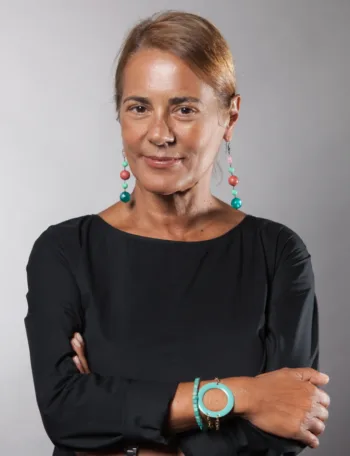 Ritratto professionale di Rita Schirinzi, Head of Marketing di Invesco Italy, con abito nero ed accessori turchesi, su sfondo neutro.