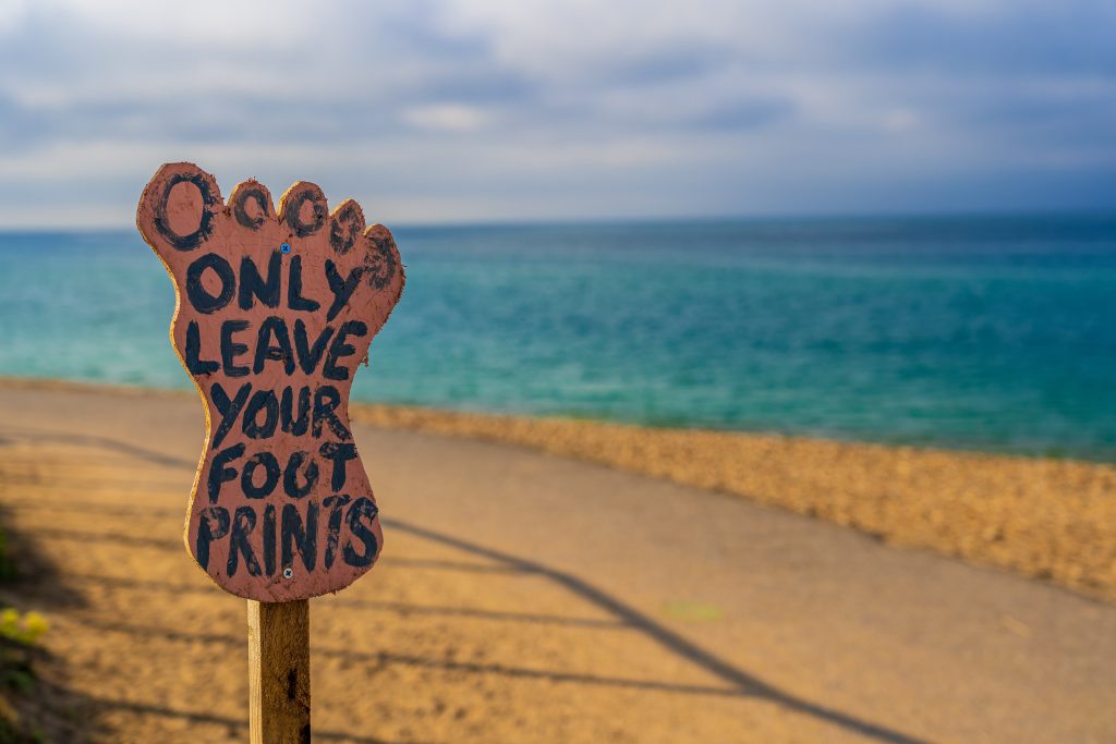 Cartello su una spiaggia con la scritta Leave only your footprints