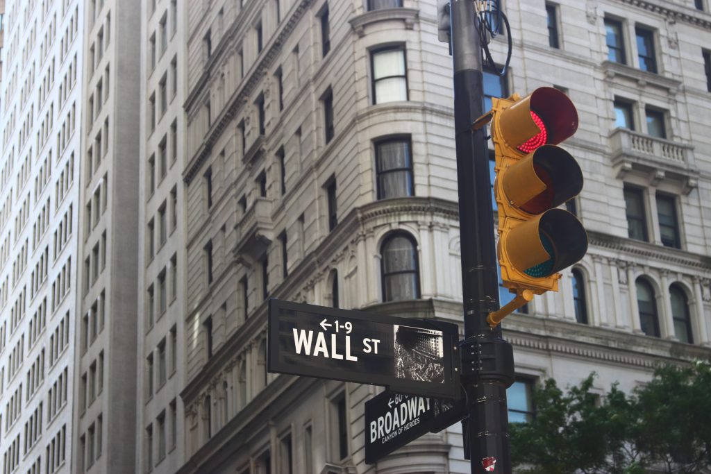 Un cartella che indica la direzione di Wall Street davanti a un semaforo rosso