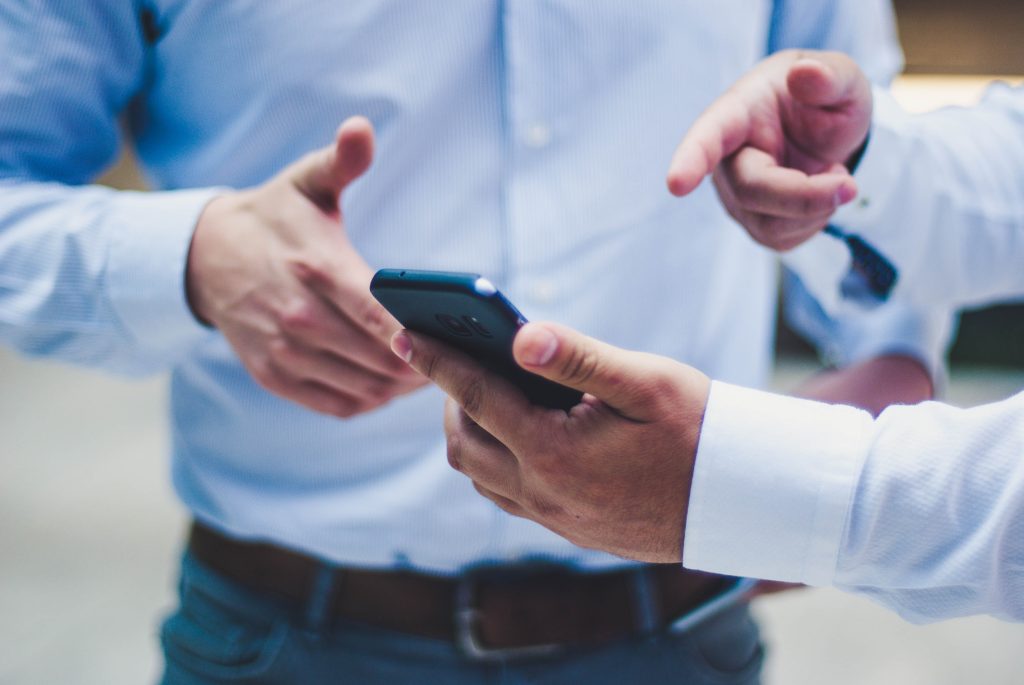 Un consulente mostra a un cliente l'andamento degli investimenti sullo schermo di uno smartphone