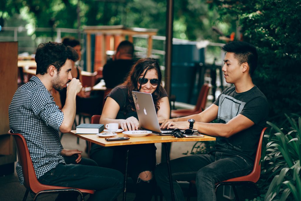 Millennials lavorano seduti al tavolino di un bar