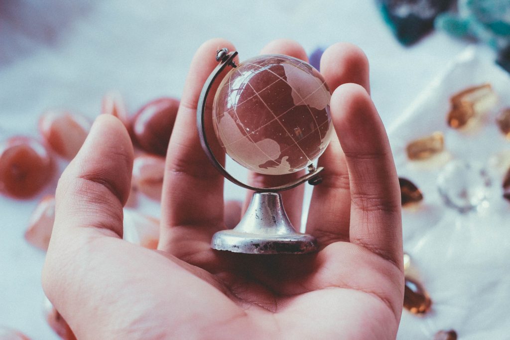 Un mini mappamondo in vetro tenuto in palmo di mano