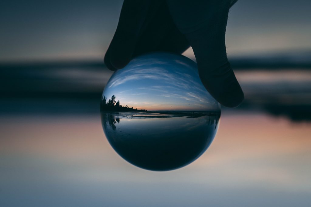 Una sfera riflette il tramonto su un paesaggio marino