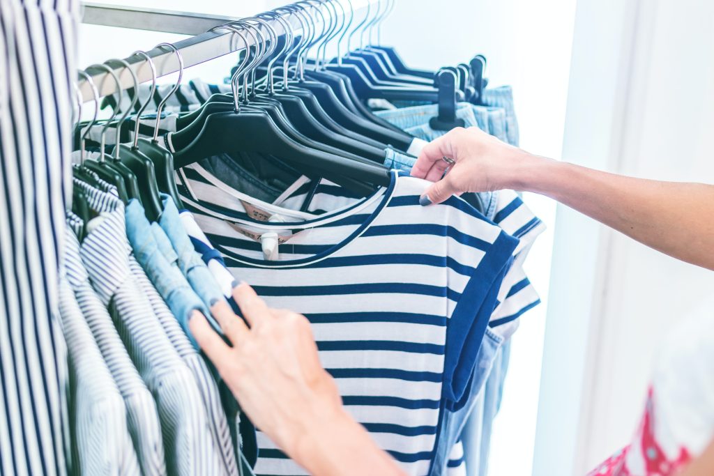 Un cliente seleziona la taglia di una maglietta a strisce orizzontali bianche e blu
