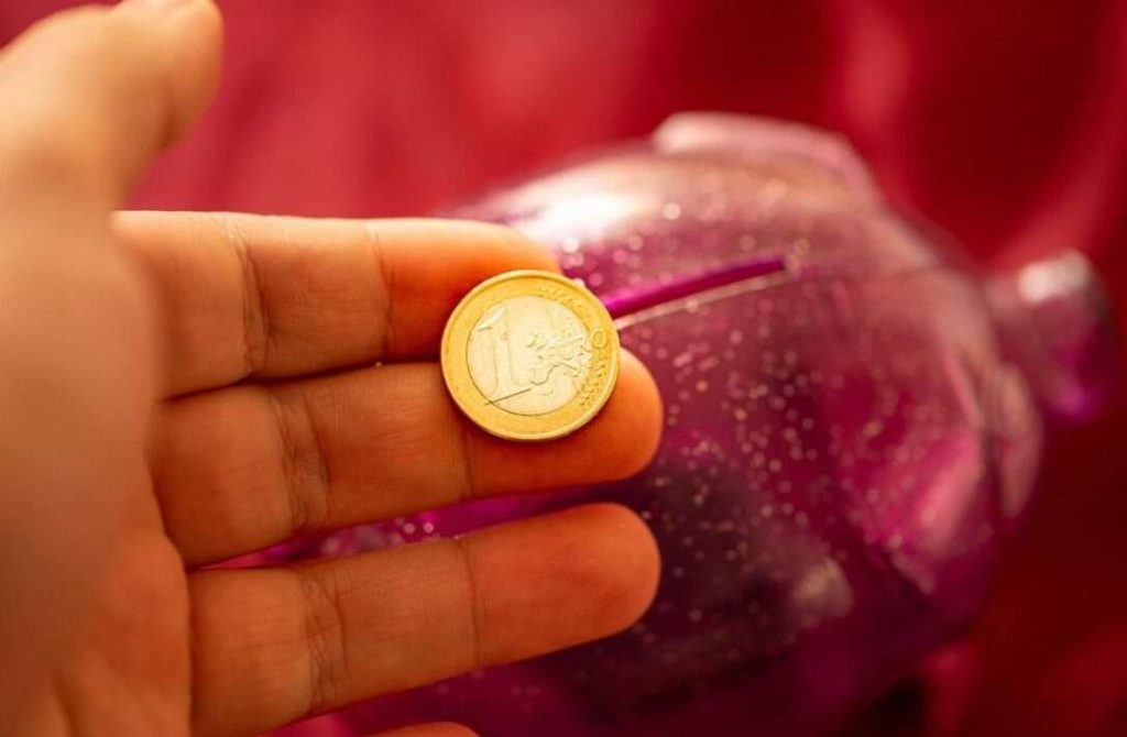 Una moneta da un euro sta per essere inserita in un salvadanaio a forma di porcellino