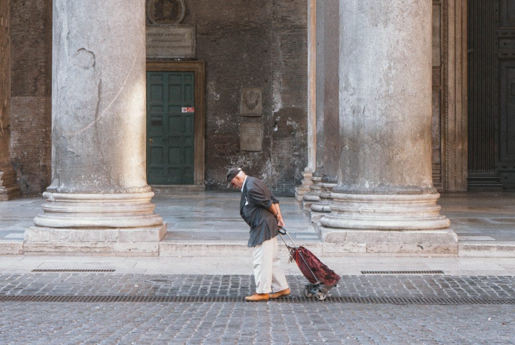 Un pensionato traina il carrellino della spesa passando davanti al Pantheon a Roma