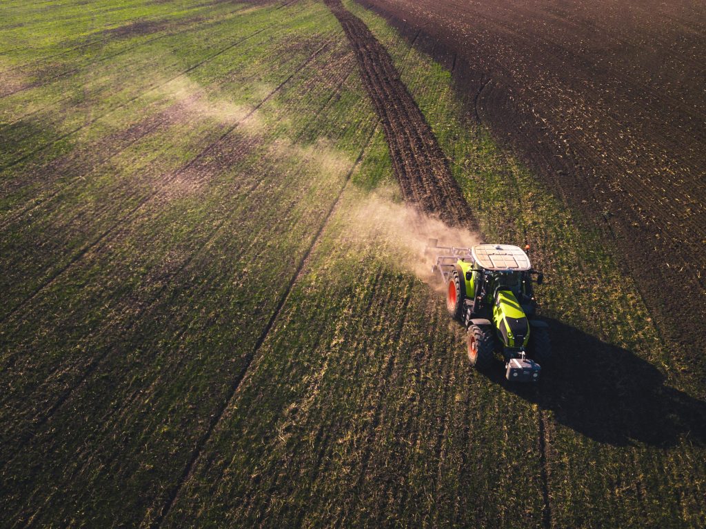 Un trattore ripreso dall'altro mentre ara un campo preparandolo per la coltivazione