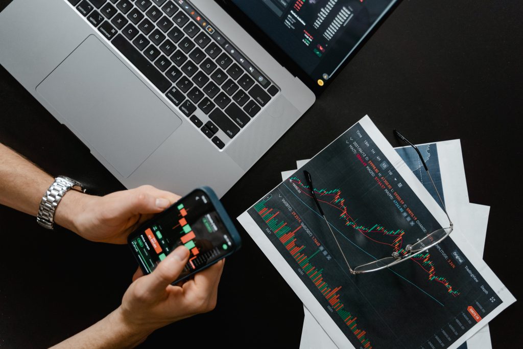 Nella foto di Tima Miroshnichenko, un trader opera utilizzando il suo smartphone, il suo pc e slide sull'andamento delle Borse