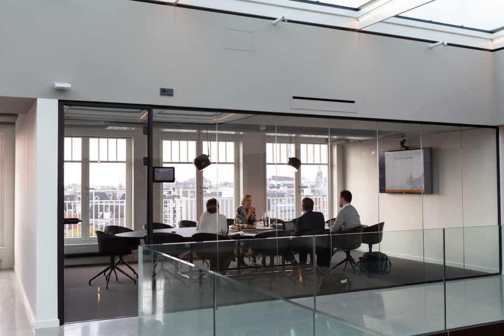 Quattro manager all'interno di una sala riunioni con vetrate