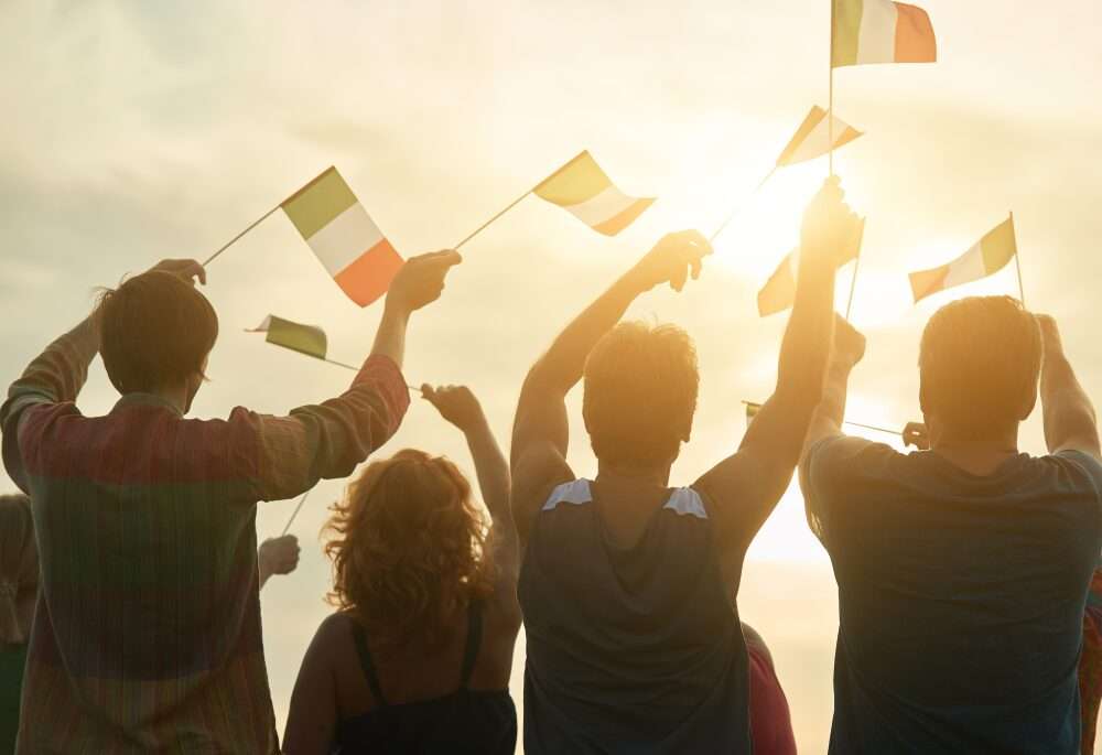 Persone viste di spalle in controluce sventolano delle bandierine italiane