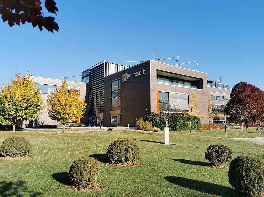 Nell'immagine, sullo sfondo di un prato verde e con un cielo azzurro, una costruzione color marrone chiaro. A Budapest, la sede Graphisoft Park di Microsoft. La foto è di Elekes Andor, Wikimedia Commons