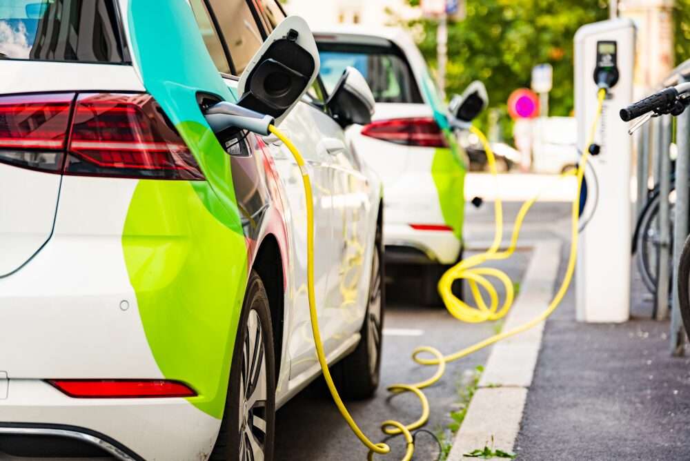 L'immagine mostra delle automobili in carica presso distributori di energia elettrica