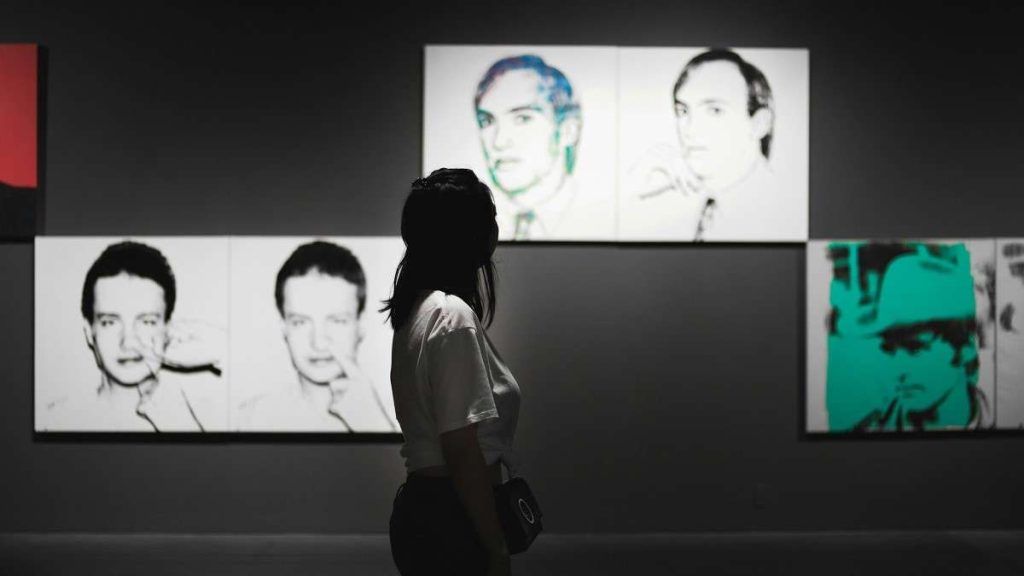 Una visitatrice ammira i quadri di Andy Warhol in un museo