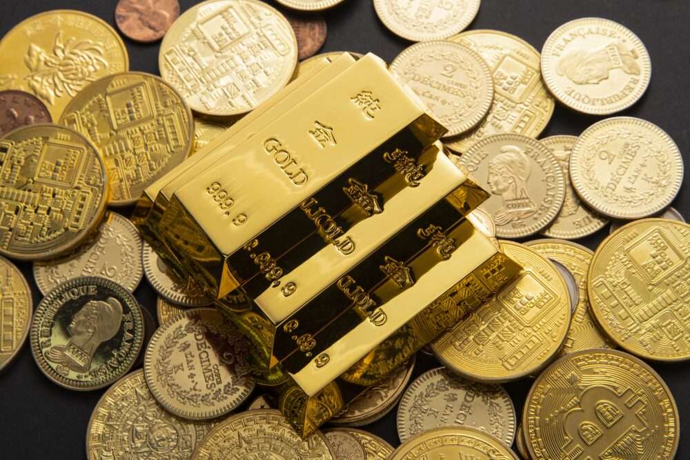 Nell'immagine tre lingotti d'oro poggiati su alcune monete, sempre d'oro