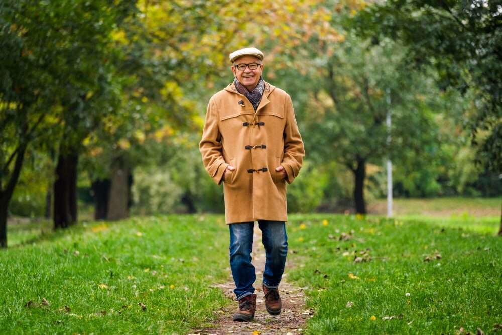 L'immagine mostra un pensionato arrivo e in buona salute che passeggia in un parco