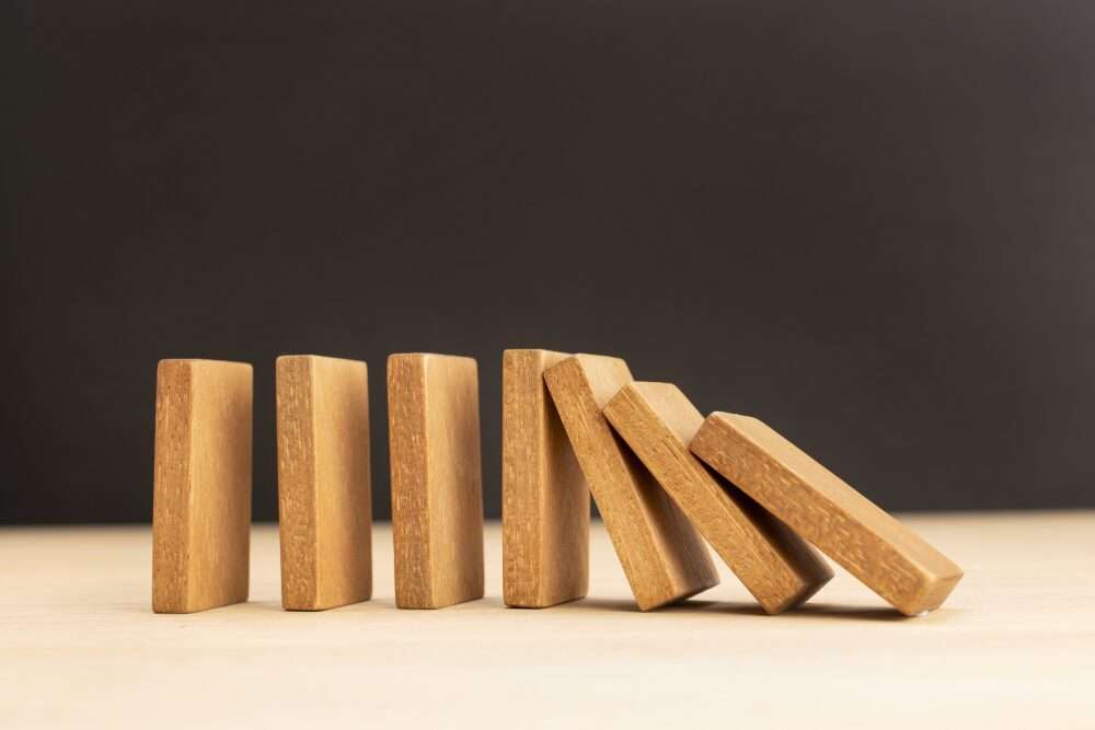 L'immagine mostra sette mattoncini del domino, in legno, durante la caduta