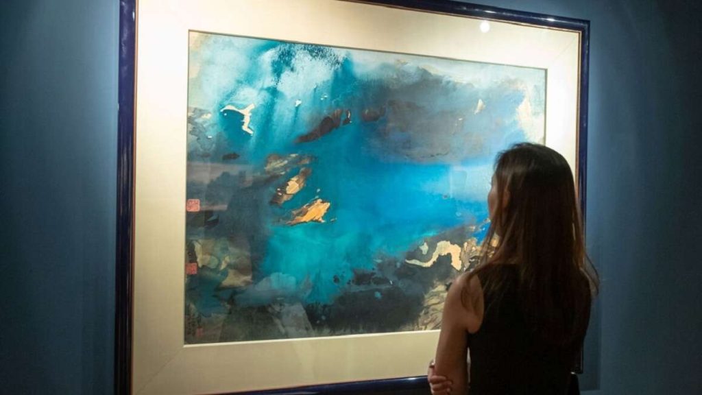 Una donna ammira un'opera di Zhang Daqian