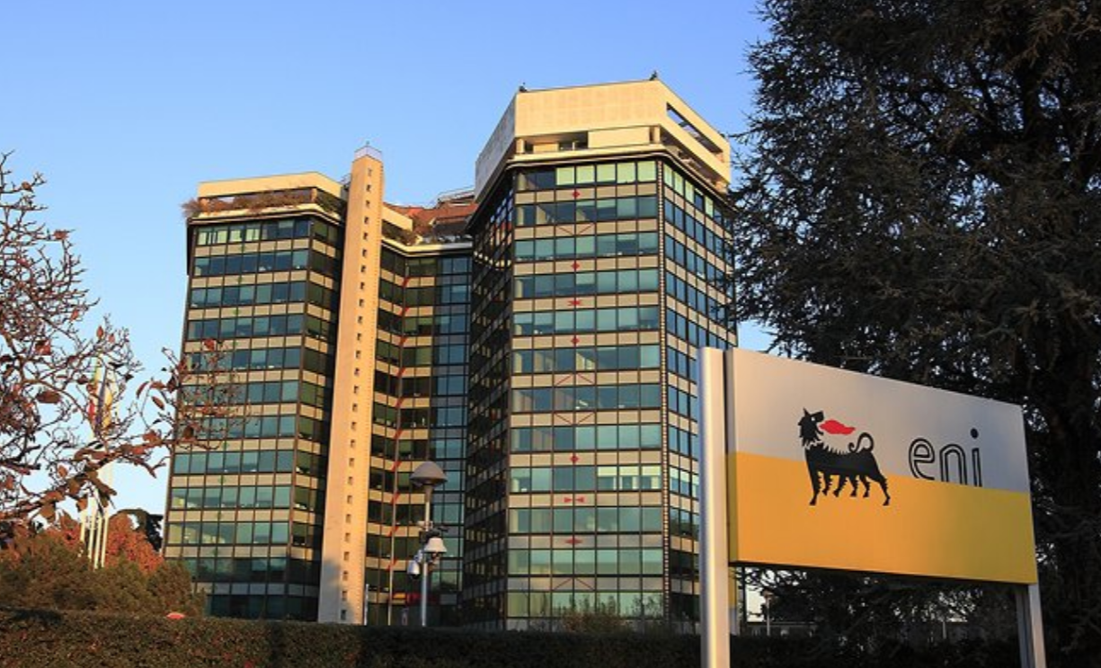 Sede centrale di ENI a Milano, Italia. Edificio moderno con vetri riflettenti e logo ENI su un'insegna, simbolo della compagnia energetica italiana. Fotografia al tramonto.