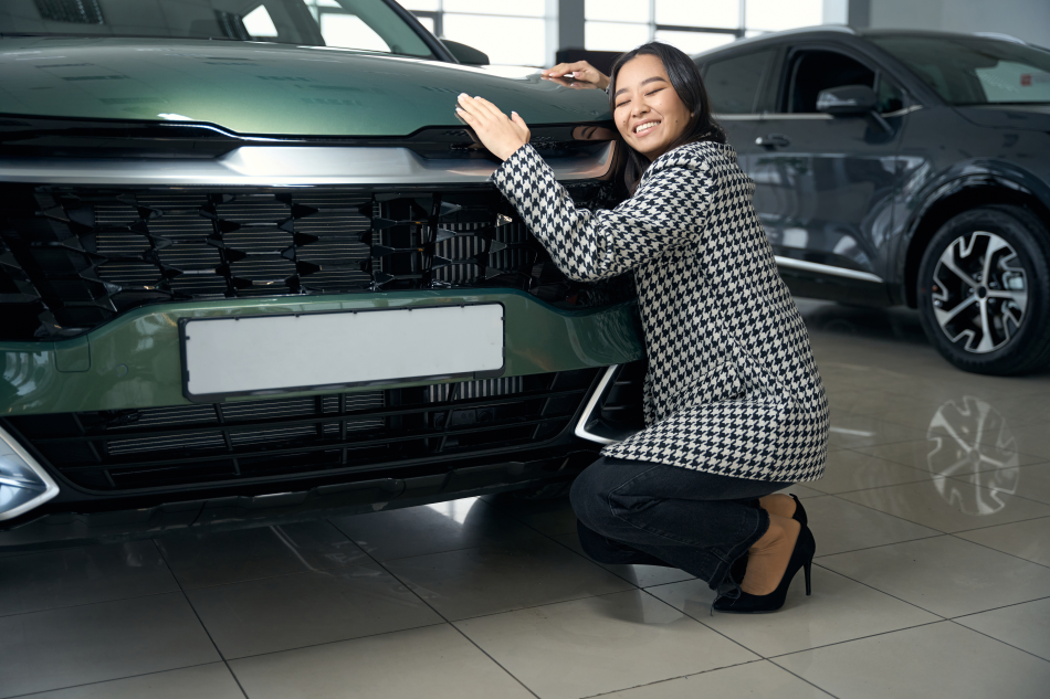 Nell'immagine, una donna cinese abbraccia un automobile in un concessionario