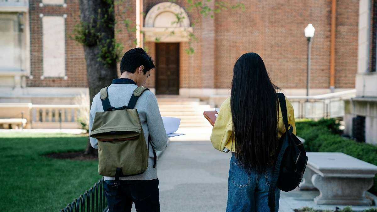 Uno studente e una studentesse camminano nel campus di un'università