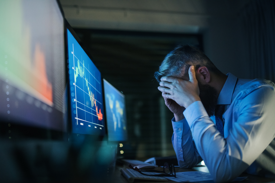 L'immagine mostra un trader disperato davanti agli schermi che mostrano l'andamento dei mercati azionari
