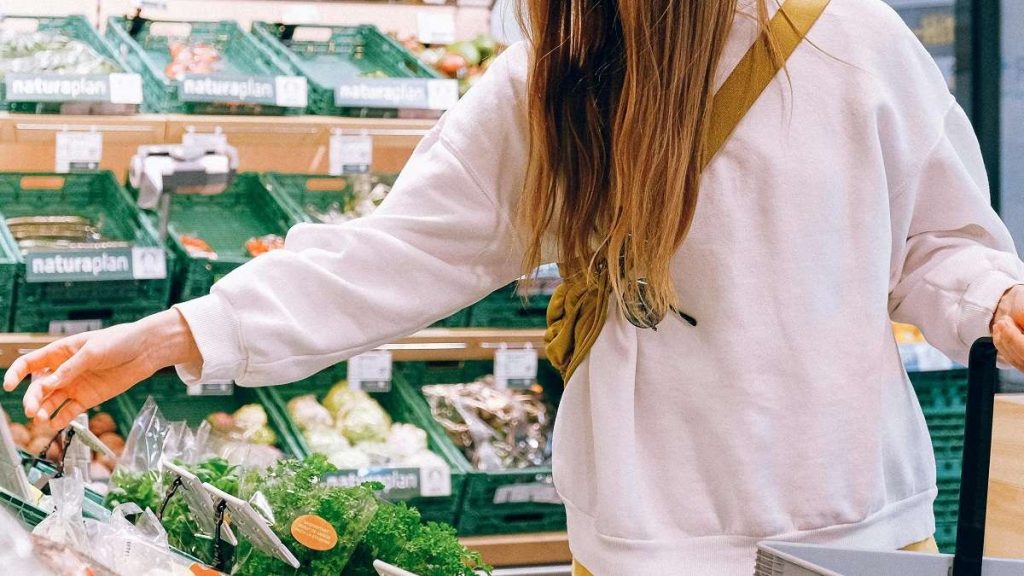 Una donna fa la spesa di verdura in un supermercato