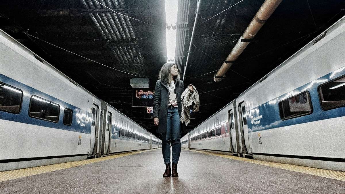 Una donna tra due treni in una stazione ferroviaria