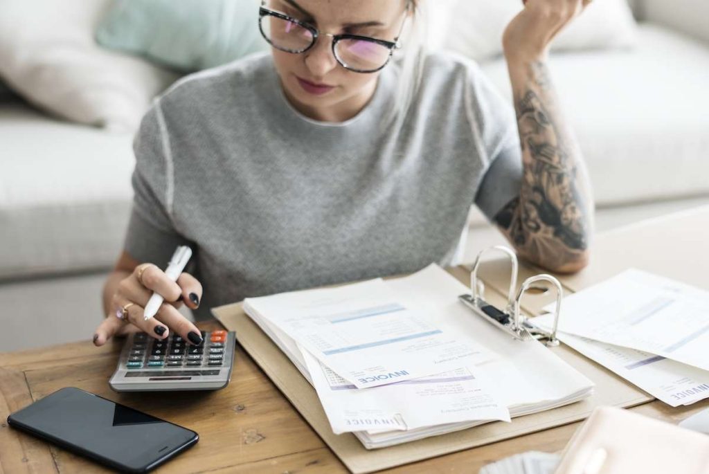 Donna che gestisce fatture e contabilità con calcolatrice e documenti: fatturazione elettronica e gestione finanziaria 2025