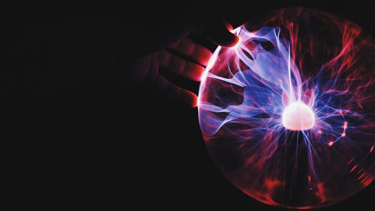 Una mano tocca una sfera al plasma