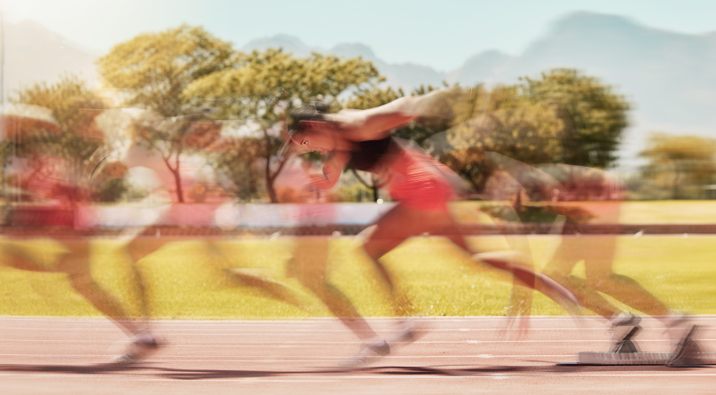 Atleta che corre su pista con effetto di movimento sfocato, rappresentando velocità, fitness e competizione all'aperto su una pista da corsa in una giornata soleggiata