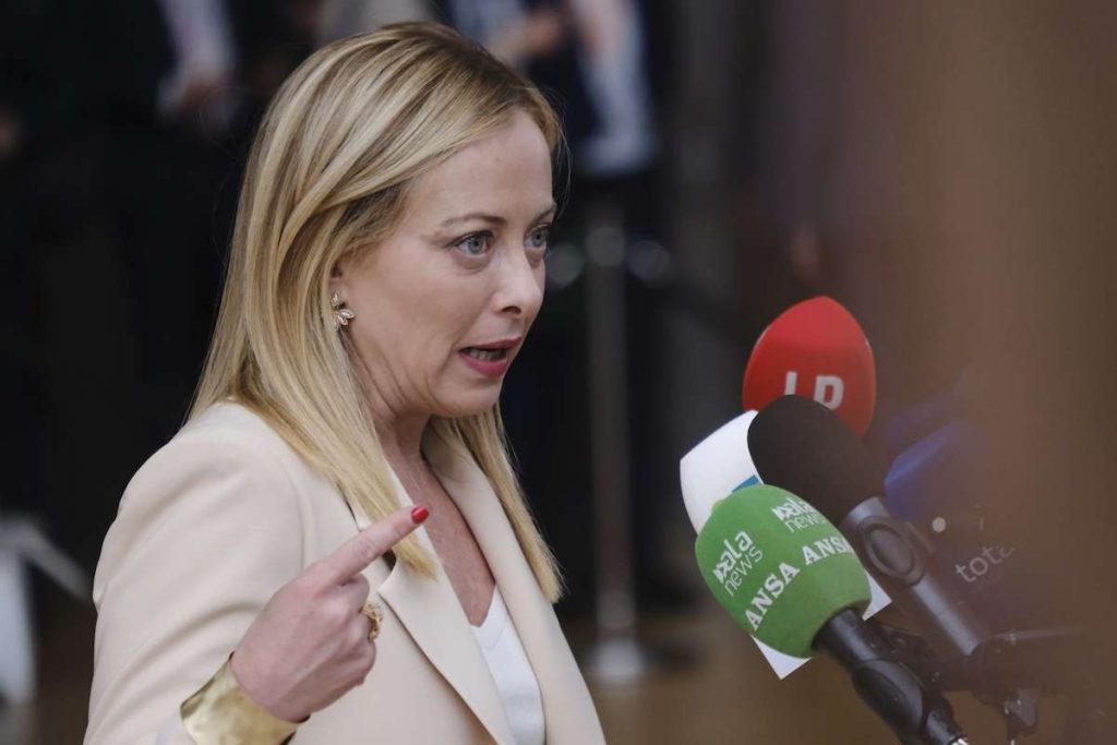 Giorgia Meloni parla ai microfoni durante una conferenza stampa, con microfoni di diverse testate giornalistiche. Discorso sulle novità Manovra 2025 in tema detrazioni fiscale.