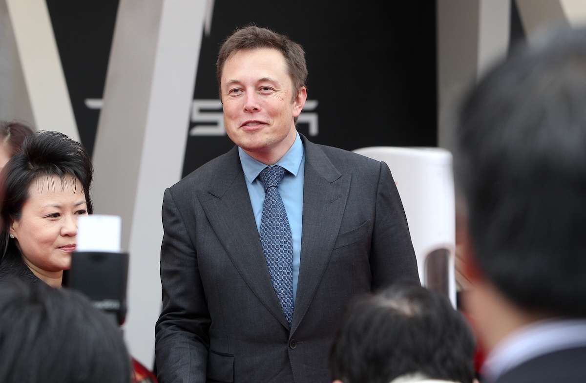 Elon Musk in giacca e cravatta, personalità di rilievo circondata da giornalisti e fotografi dopo le elezioni usa 2024