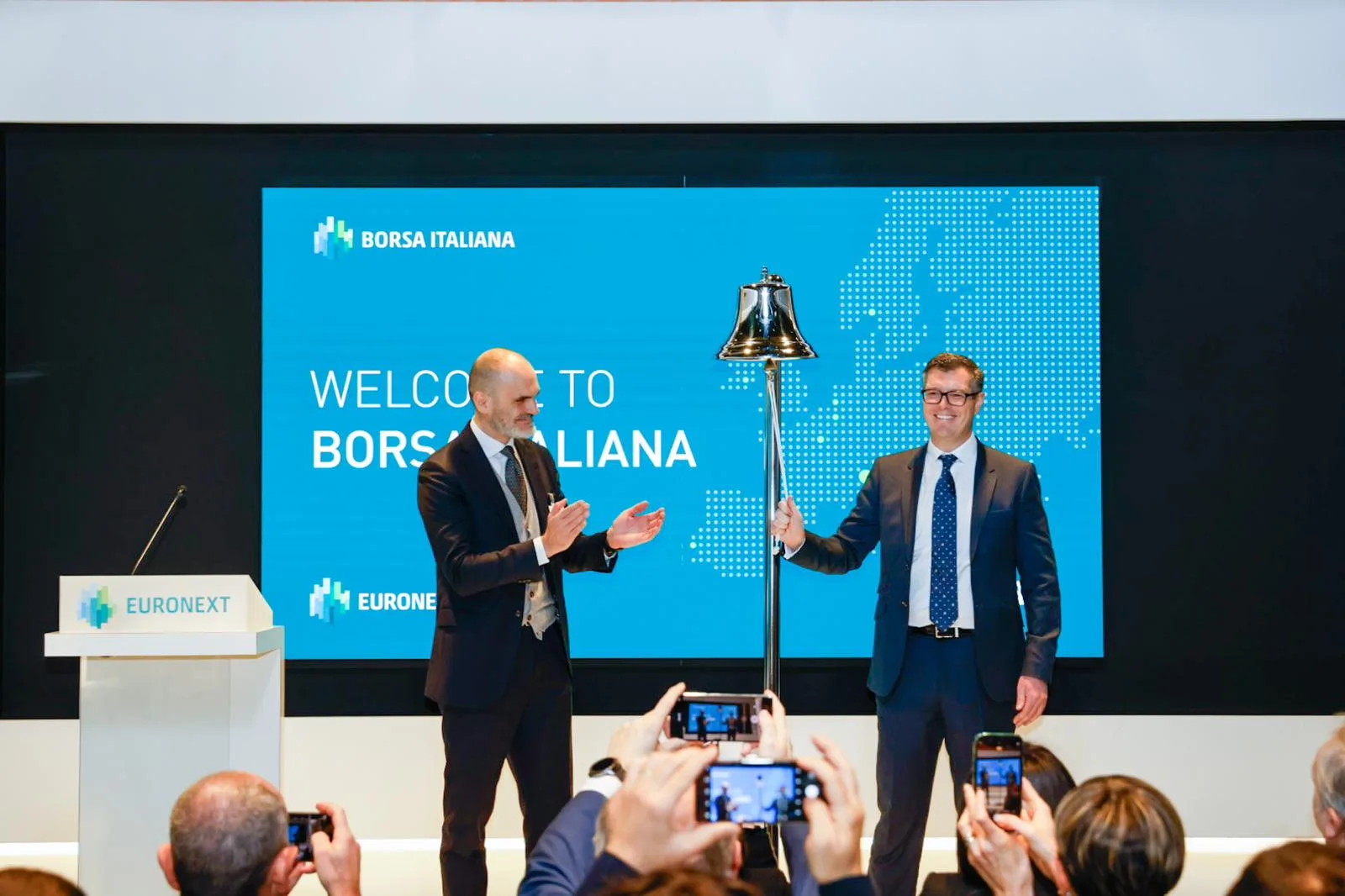 Marcello Matranga e Nick King suonano la campana argentata dell'avvio di quotazione su Borta Italiana. Alle loro spalle uno schermo mostra la data della quotazione