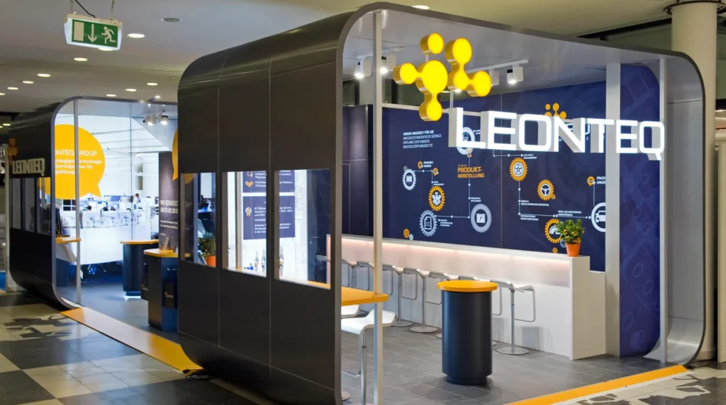 Due box di Leonteq pronti per una fiera di settore. Di forma cubica, aperti sui lati e con un banco sul fronte, riportano la scritta e il logo di Leonteq sui lati