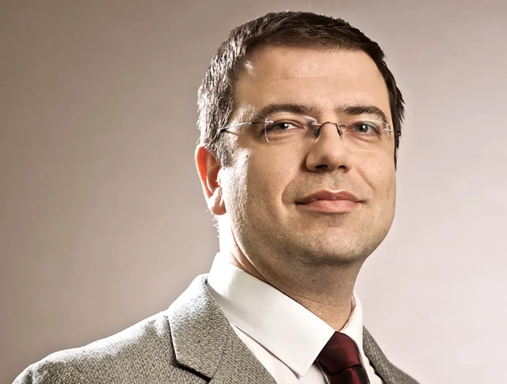 Un primo piano di Massimo Siano di 21Shares con giacca beige, cravatta bordeaus e camicia bianca