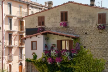 Case in pietra e intonaco in un borgo antico italiano con balconi decorati da fiori colorati e piante rampicanti, situate a Palena, Abruzzo. Architettura rustica tipica e atmosfera tranquilla di un paese montano italiano