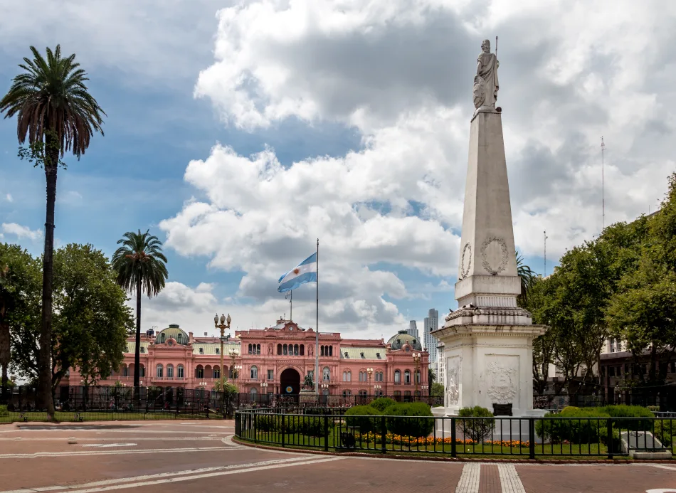 La Casa Rosada, palazzo del governo argentino, in Plaza de Mayo a Buenos Aires. Sullo sfondo il palazzo color rosa antico, la piazza è circondata da alberi. In primo piano l'obelisco