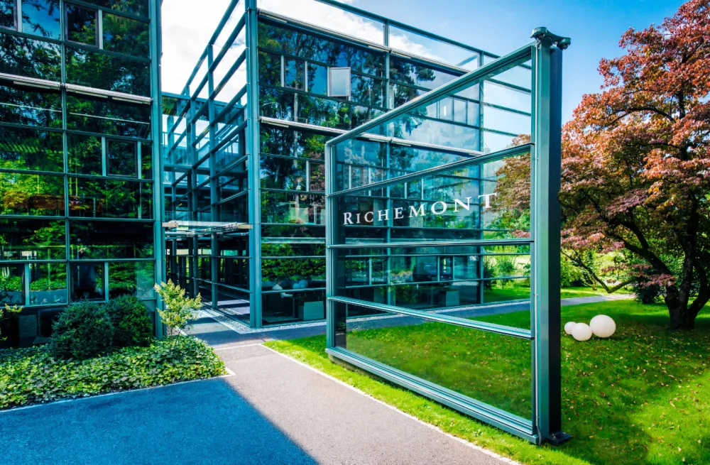L'ingresso del quartier generale di Richemont, un edificio di vetri e tubi con un passaggio pedonale circondato da erba.