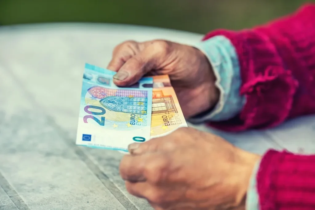 anziano con in mano soldi della pensione di febbraio 2025