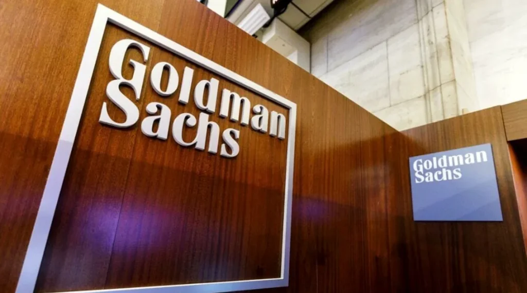 Logo Goldman Sachs all'interno della sede aziendale, con pannelli in legno e pareti in marmo. Banca d'investimento globale, servizi finanziari e gestione patrimoniale.