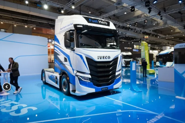 Camion Iveco Fuel Hero a idrogeno esposto a una fiera dell'autotrasporto, con design aerodinamico e livrea bianca e blu.