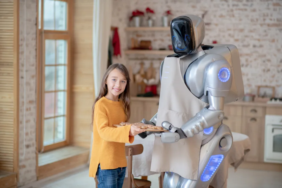 Un robot umanoide per l'aiuto domestico indossa un grembiule all'interno di una cucina. Sta mantenendo un vassoio dal quale una bambina prende un biscotto