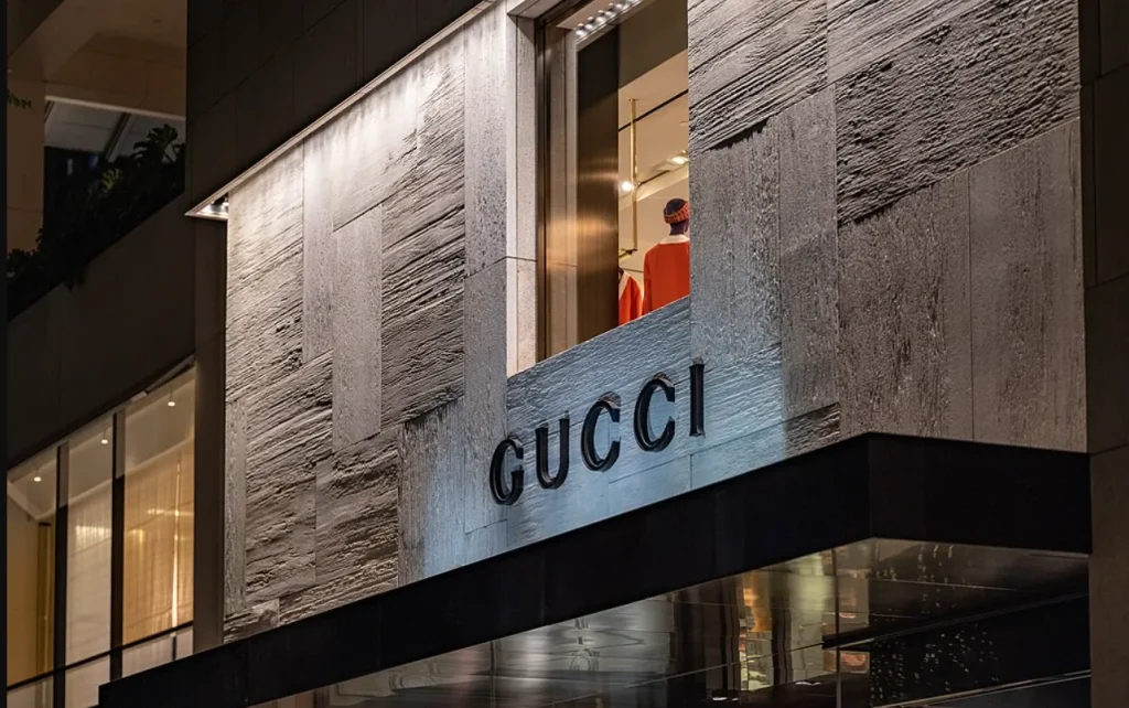 Facciata di un negozio Gucci, marchi controllato da Kering, alle Hawaii con logo illuminato e vetrina espositiva, simbolo di lusso e moda di alta gamma.
