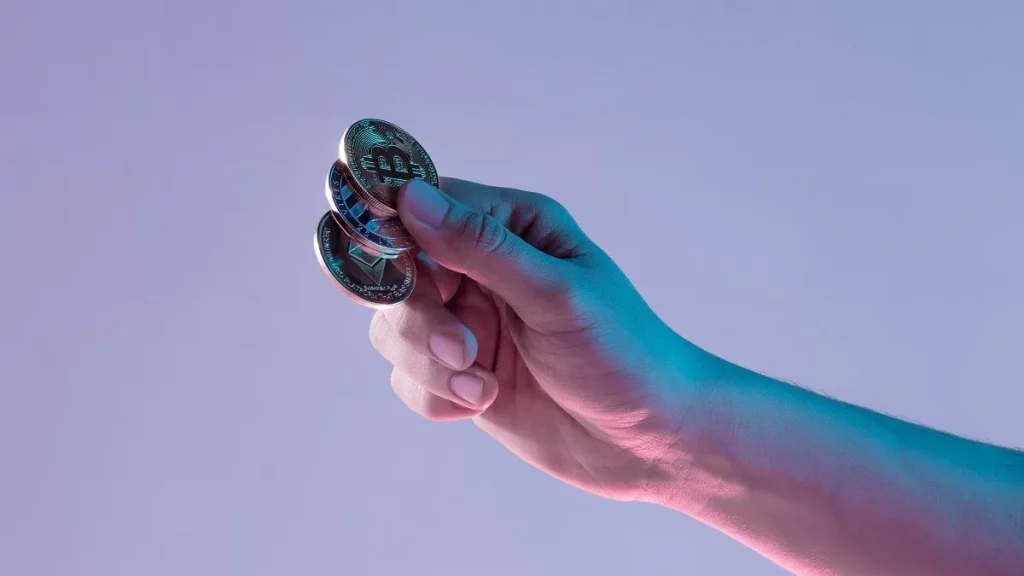 Una mano maschile che tiene i token delle principali criptovalute