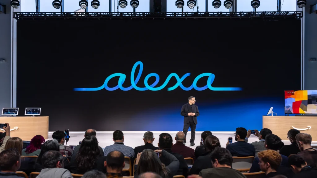 Evento di presentazione di Alexa con un relatore sul palco e il logo Alexa proiettato su un grande schermo.