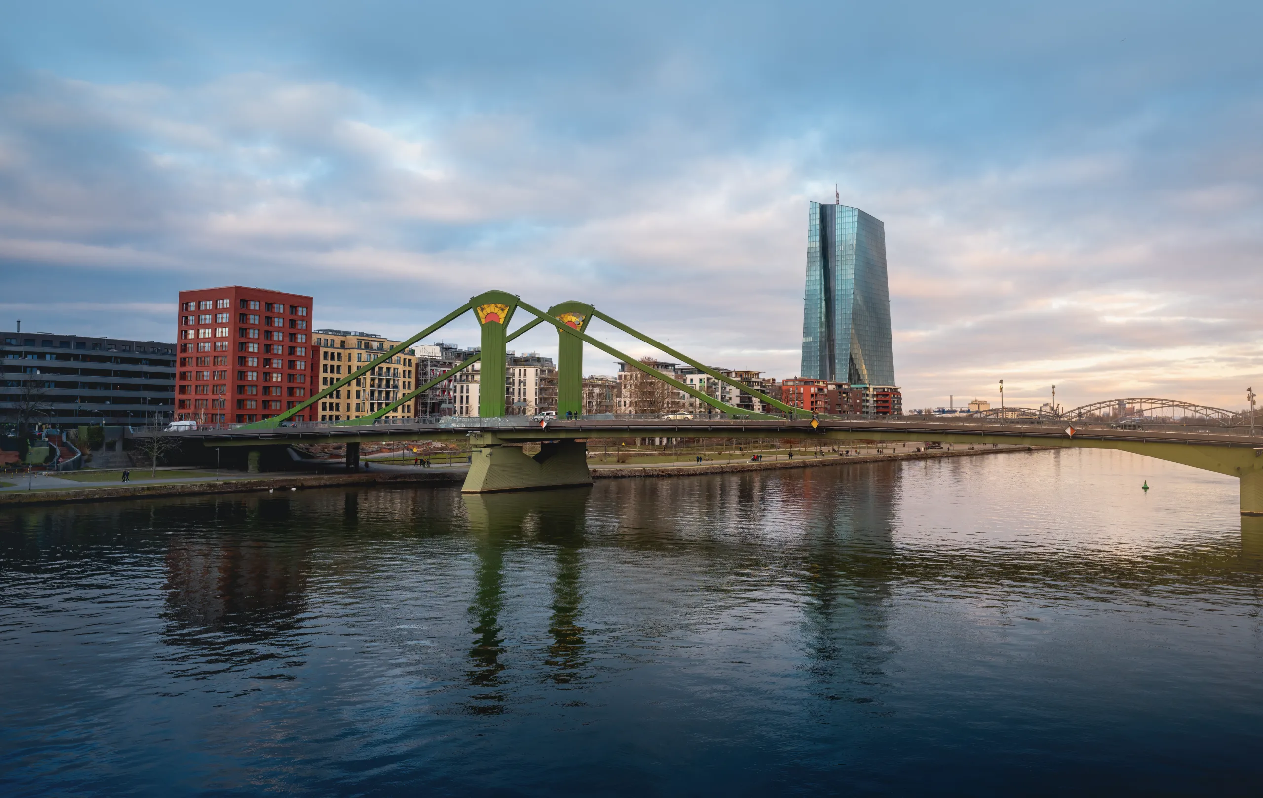 Vista panoramica del ponte Flößerbrücke e della Torre della Banca Centrale Europea (BCE) a Francoforte, con il fiume che riflette l'architettura moderna.