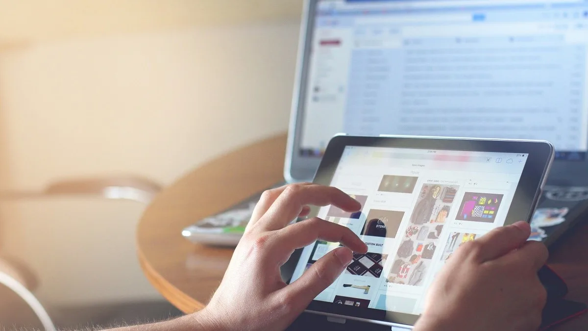 Una persona usa un iPad nero mentre è al computer