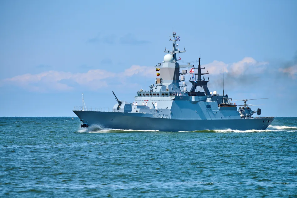 Corvetta militare in navigazione con elicottero a bordo su mare aperto sotto un cielo sereno.